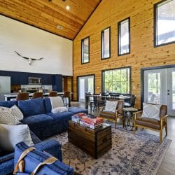 Great room with a vaulted pine ceiling, blue sofas, a longhorn skull and French doors, the kitchen behind