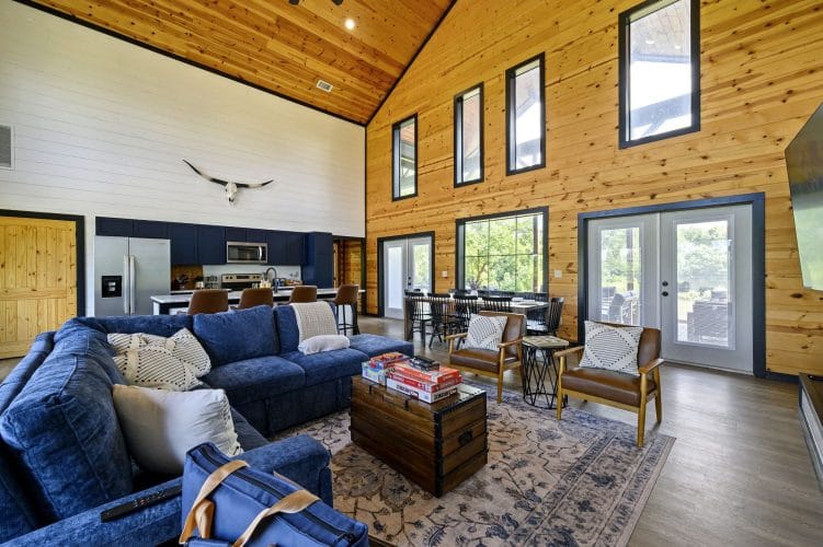 Great room with a vaulted pine ceiling, blue sofas, a longhorn skull and French doors, the kitchen behind