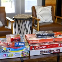 Stack of board games on a coffee table between two leather chairs