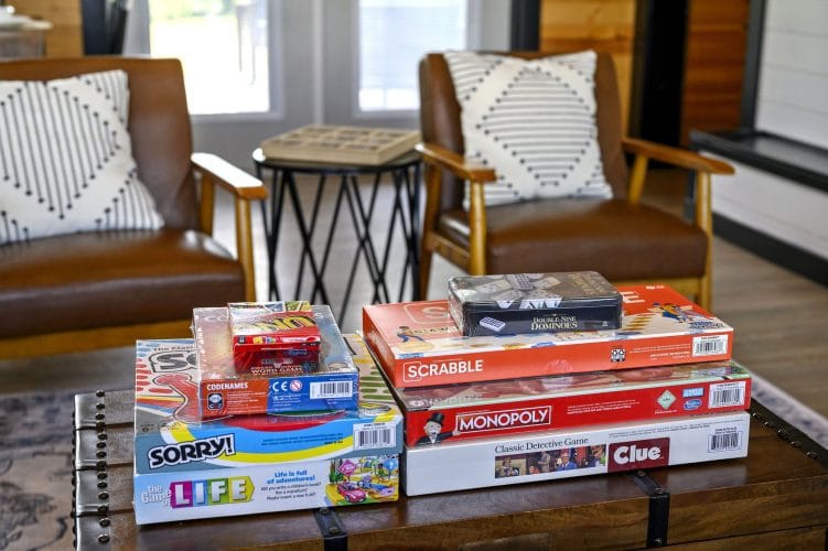 Stack of board games on a coffee table between two leather chairs