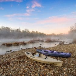 Two kayaks on a gravel bar of the river in morning mist