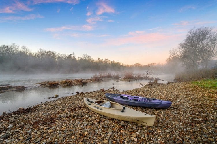 Two kayaks on a gravel bar of the river in morning mist