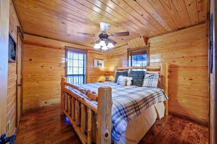 Second bedroom with a log-post bed, gray plaid comforter and a ceiling fan