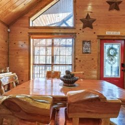 Thick slab-wood dining table with matching benches next to the red front door