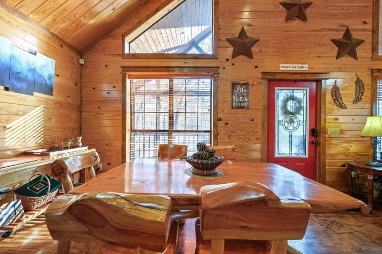 Thick slab-wood dining table with matching benches next to the red front door