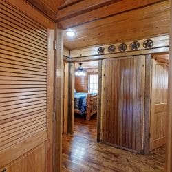 Hallway with a louvered door and a doorway leading to a bedroom