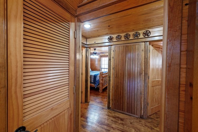 Hallway with a louvered door and a doorway leading to a bedroom