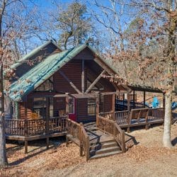 Front of the cabin with a green roof, stairs and porch (same view as photo 30, cropped square)