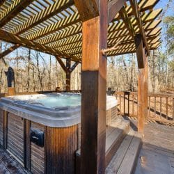 Hot tub with a wood-paneled skirt under the pergola