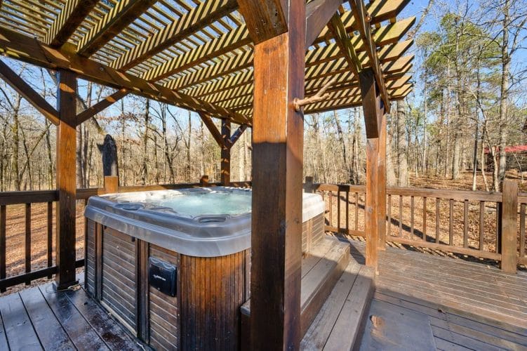 Hot tub with a wood-paneled skirt under the pergola