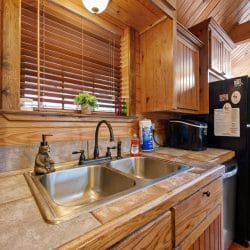 Double sink with tile countertop and a black refrigerator