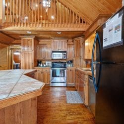 Kitchen with a tile-topped island, stainless range and microwave, and the loft railing overhead