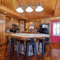 Tile-topped island with four black metal bar stools and three pendant lights