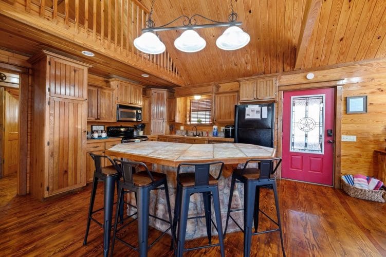 Tile-topped island with four black metal bar stools and three pendant lights