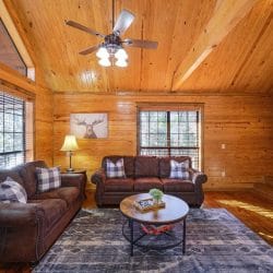 Living room with two brown sofas facing a round coffee table and a ceiling fan overhead