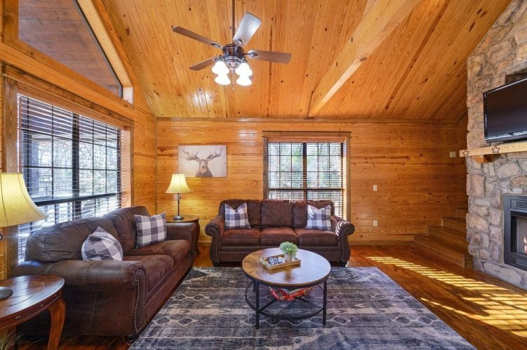 Living room with two brown sofas facing a round coffee table and a ceiling fan overhead
