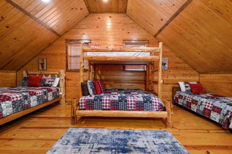 Upstairs sleeping area with a log twin-over-queen bunk in the middle and a bed on each side