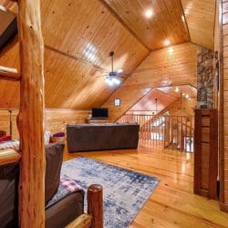 Upstairs room looking toward the stairs, with a sofa and a log bed frame in the foreground