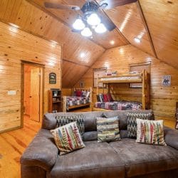 Upstairs leather sofa with the bunk bed and another bed behind it under the sloped ceiling