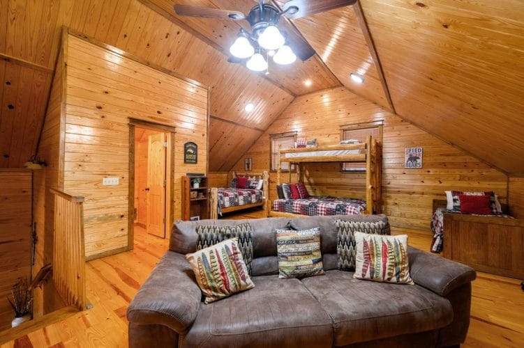 Upstairs leather sofa with the bunk bed and another bed behind it under the sloped ceiling