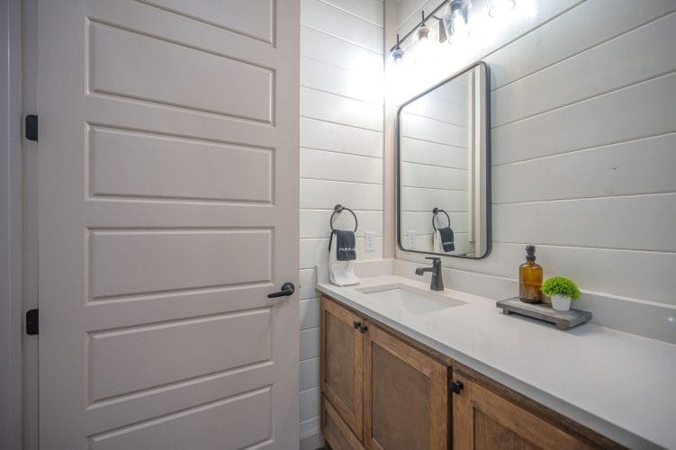Wood vanity with a black-framed mirror beside a white door