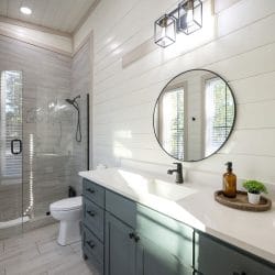Vanity with a round mirror and a glass shower