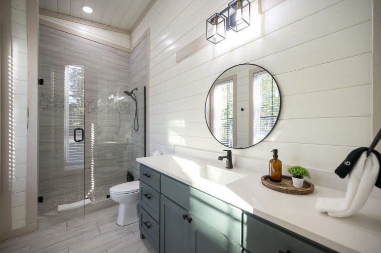 Vanity with a round mirror and a glass shower