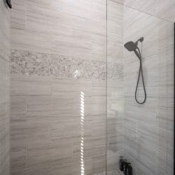 Walk-in shower with gray tile and a handheld head
