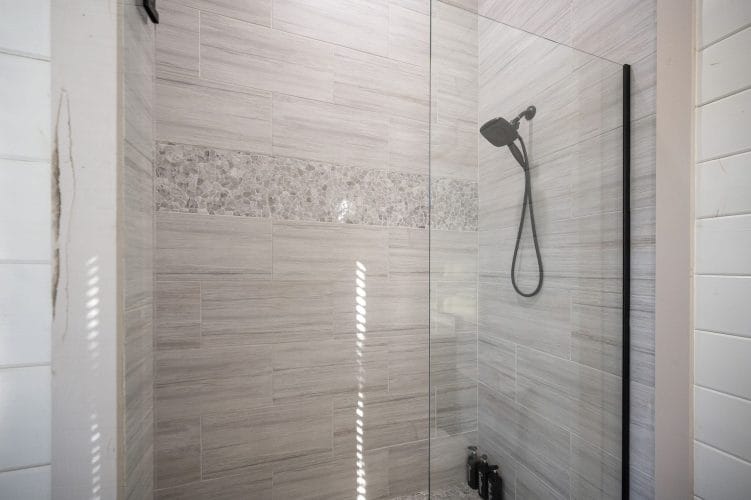 Walk-in shower with gray tile and a handheld head