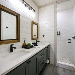 Double vanity with wood-framed mirrors and a glass shower