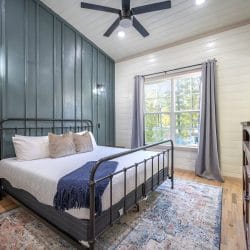 King black iron bed with a navy throw against a dark green board-and-batten wall