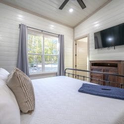 Same bedroom with a wall TV and a window with gray curtains