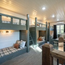 Bunk loft with plaid bedding on three bunk stacks and gray carpet