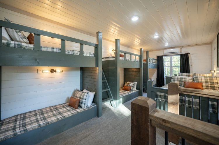 Bunk loft with plaid bedding on three bunk stacks and gray carpet