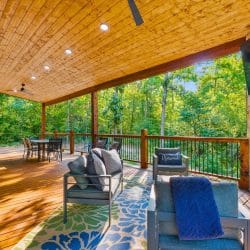 Covered deck with an outdoor sofa, a gas fireplace, a TV and a long table