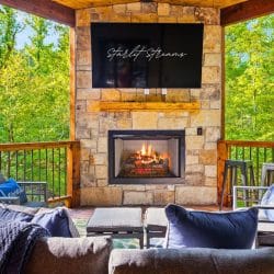 Stone fireplace with a TV above it and lounge furniture on the covered deck