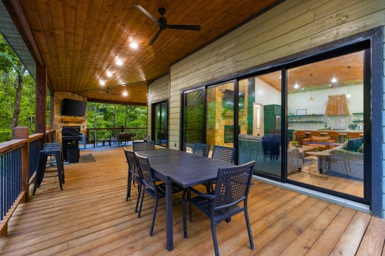 Covered deck with a dining table, a grill and sliding doors into the kitchen