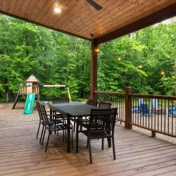 Long deck with a dining table, and a view down to the fire pit and playset