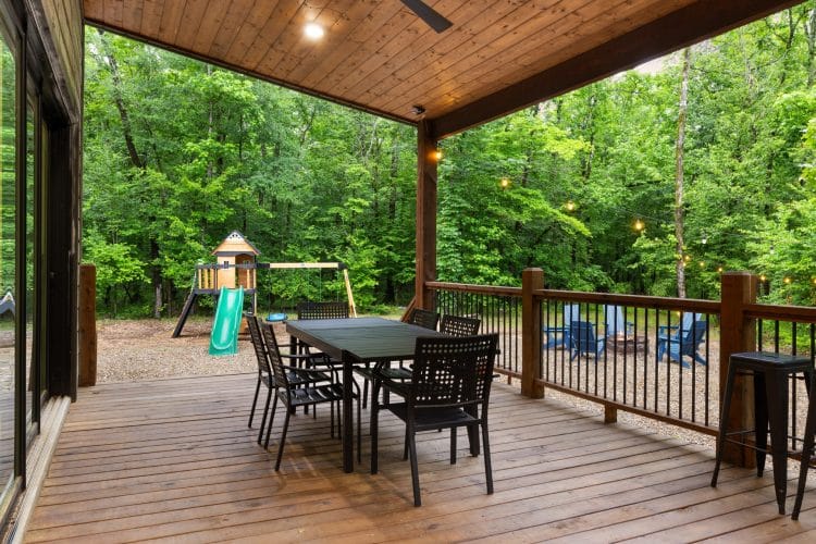 Long deck with a dining table, and a view down to the fire pit and playset