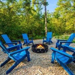 Fire pit with bright blue Adirondack chairs on a gravel pad