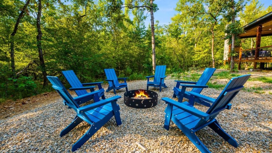 Fire pit with bright blue Adirondack chairs on a gravel pad