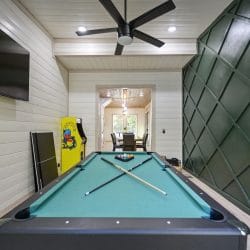 Pool table in the game room with a Pac-Man cabinet and a green paneled wall