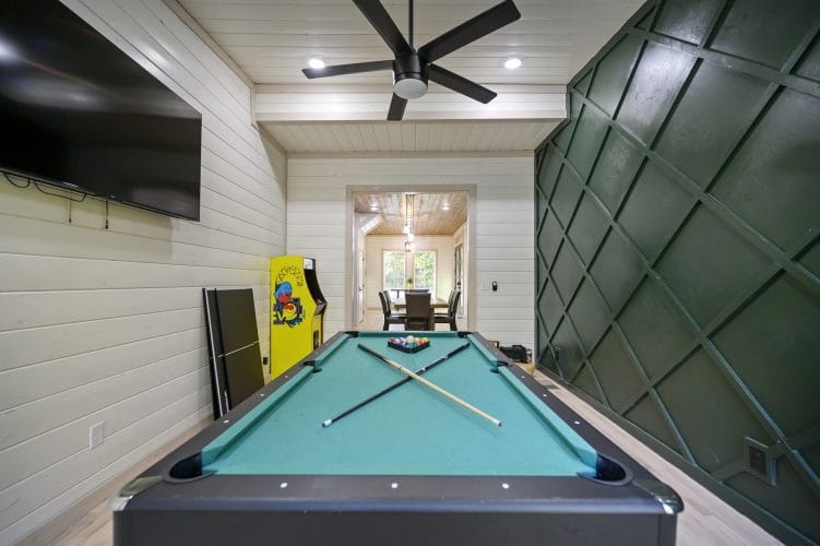 Pool table in the game room with a Pac-Man cabinet and a green paneled wall
