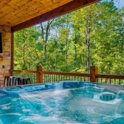 Hot tub on the covered deck with a stone fireplace and TV behind it