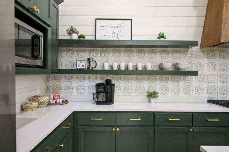Open green shelves with dishes, a coffee maker and a patterned backsplash