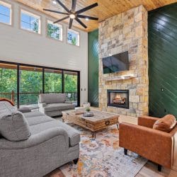 Great room with a wall of sliding glass doors to the deck and a stone fireplace