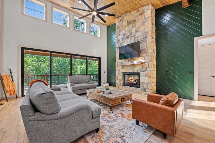 Great room with a wall of sliding glass doors to the deck and a stone fireplace