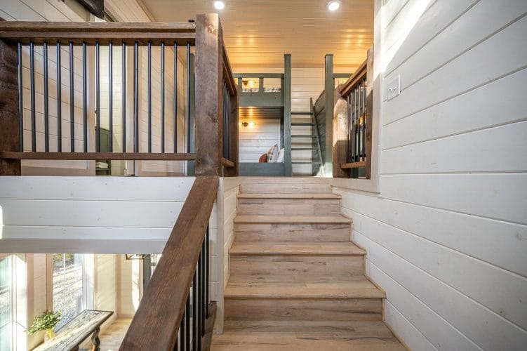 Open stairs with a railing leading up to the loft, with bunks visible at the top