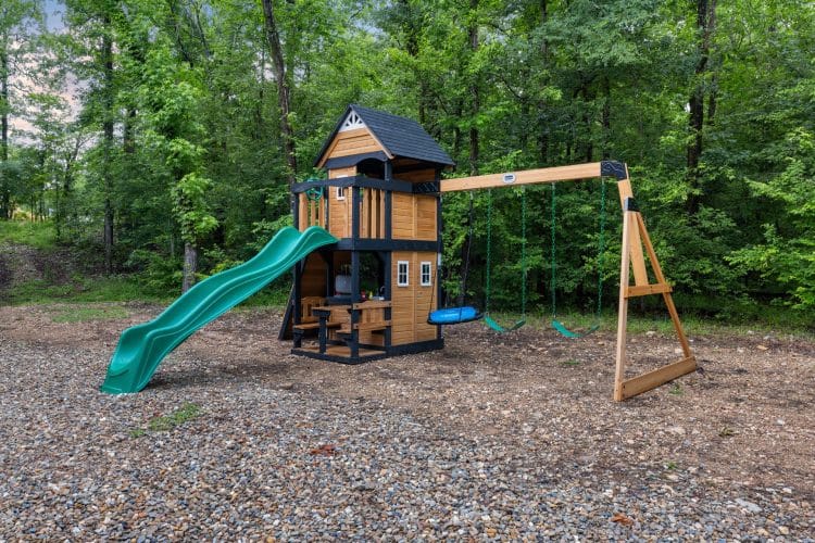 Playset with a green slide, a cedar tower and swings