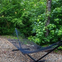 Hammock strung between trees on a gravel pad under string lights
